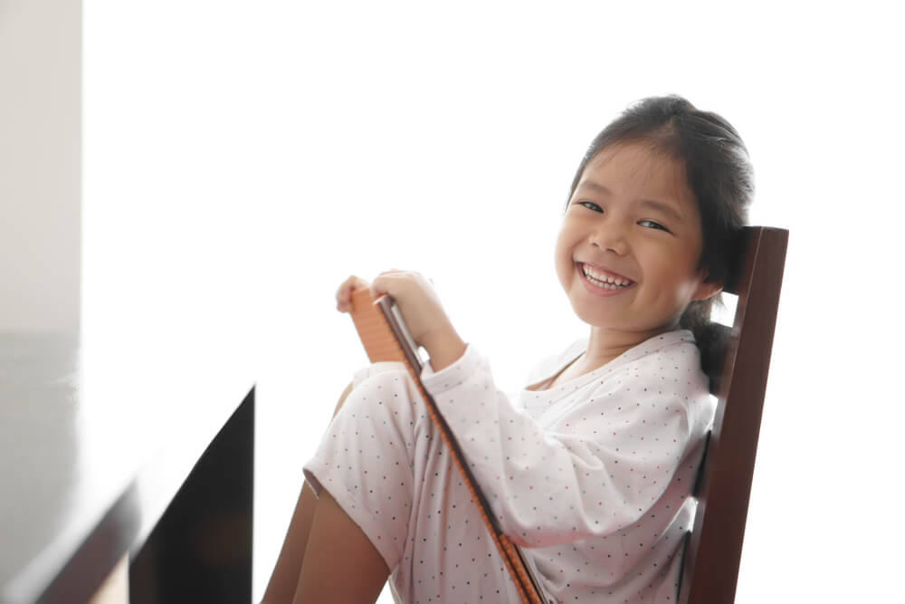 young-girl-smiling-while-sitting-on-a-chair