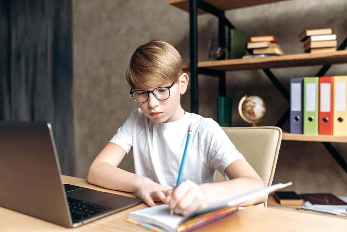 child studying at home brushing teeth learning oral hygiene habits with laptop